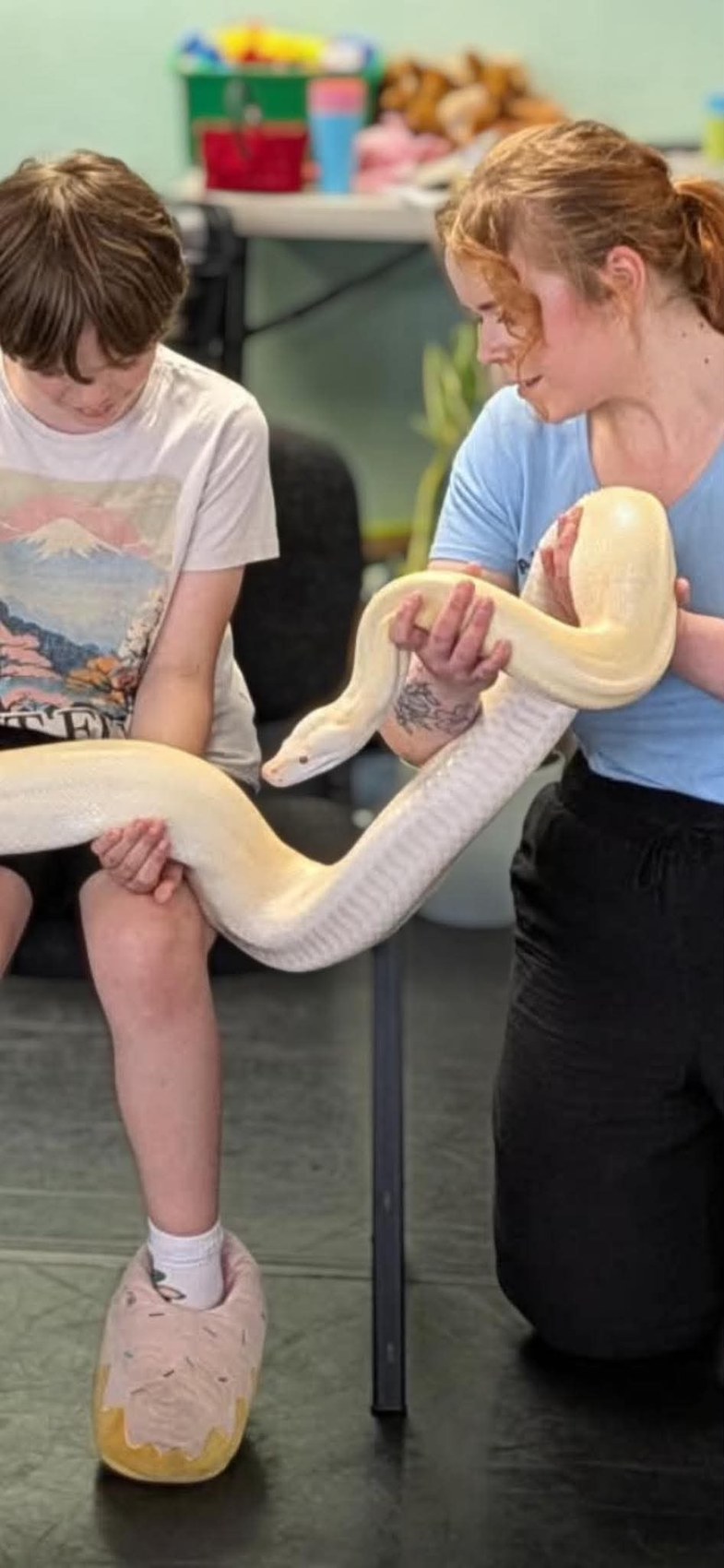 A large pale snake being supported by several people